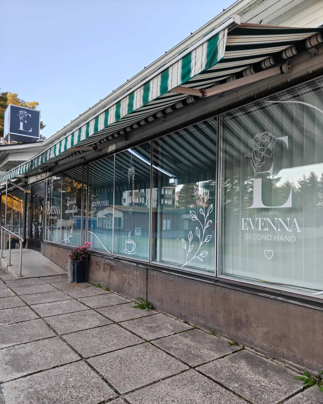 Secondhand Evennan liikkeen julkisivu Iissä: ikkunarivi valkoisine teippauksineen, joissa logo, kahvio ja kirpputori.